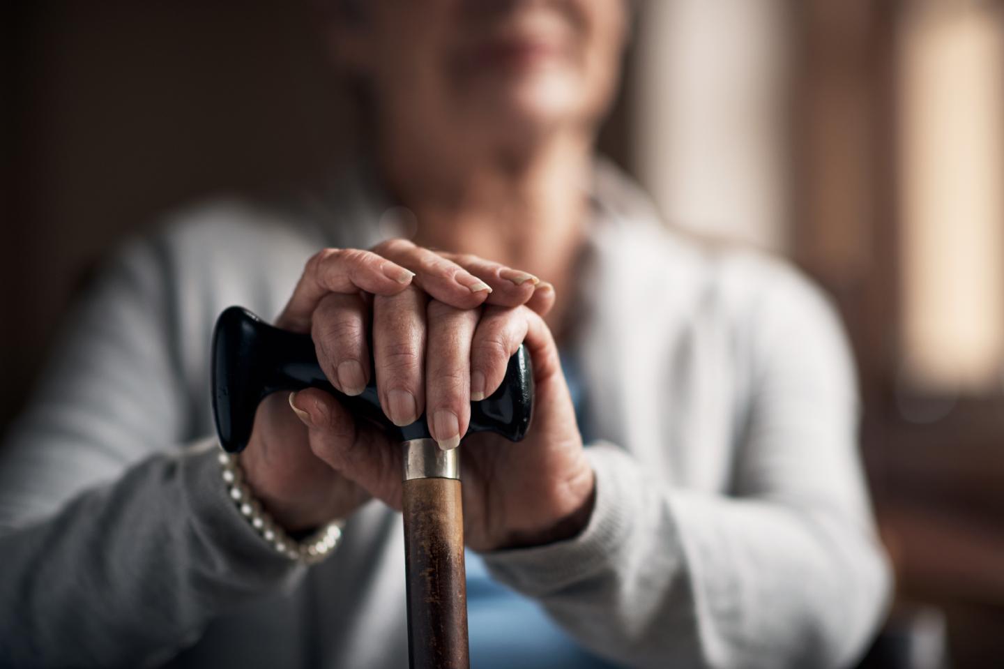 Shot of a senior woman sitting and holding a wooden cane.