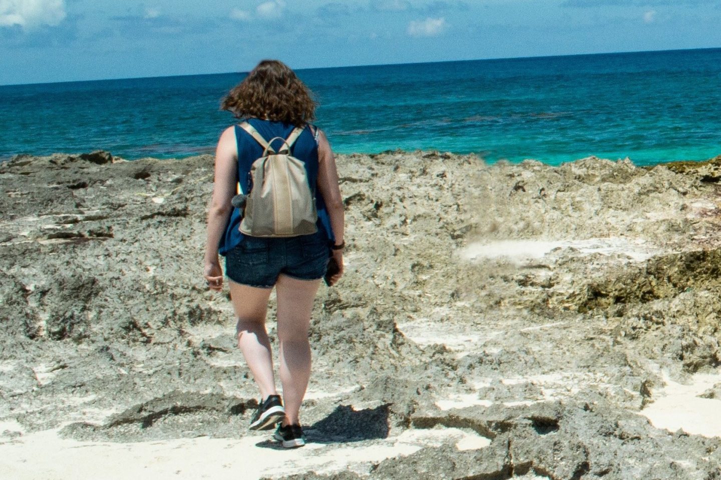 Woman wearing a backpack walks at a beach