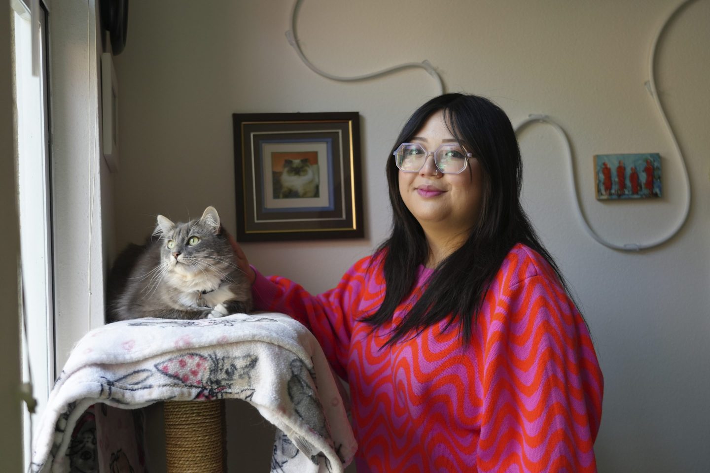 Celina Chanthanouvong stands with her cat in her apartment in Emeryville, Calif., on June 2, 2023. The pause in repayment has been a lifeline keeping 25-year-old Chanthanouvong afloat.