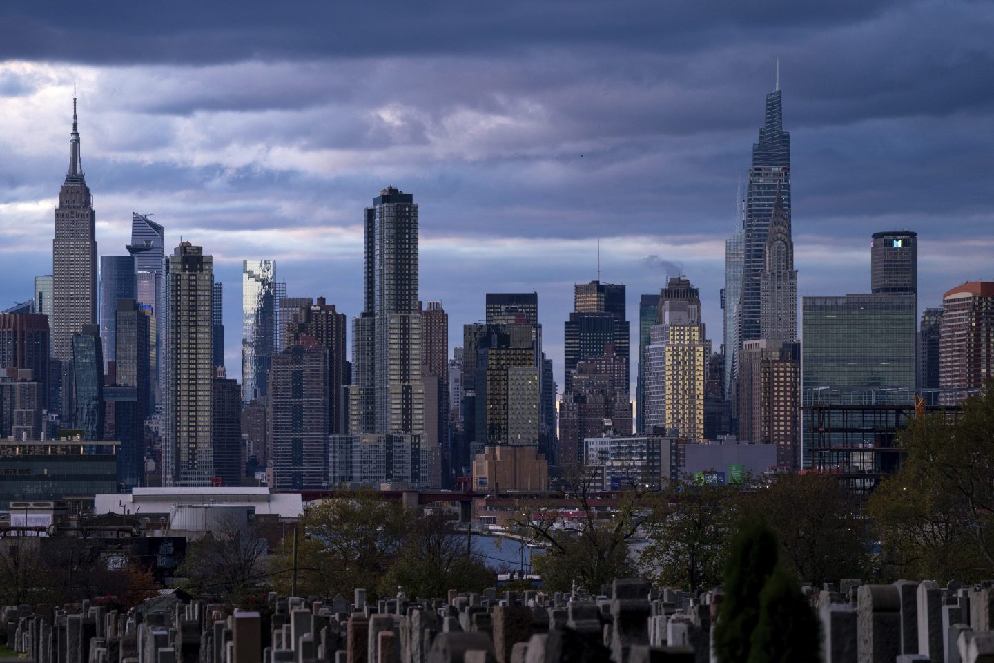 The sun sets behind the New York skyline, on Nov. 13, 2022, as seen from Calvary Cemetery. 