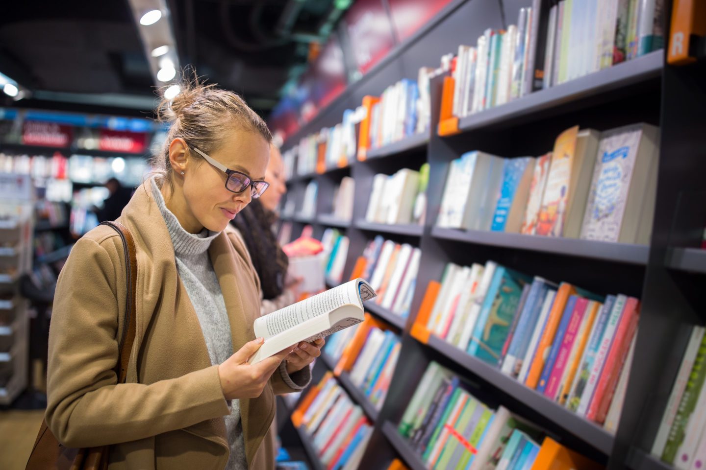 A lady browsing through a book at a bookstore