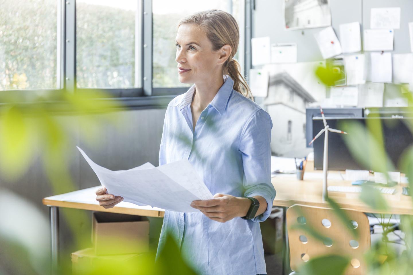 Woman in office working on plan with wind turbine model on table