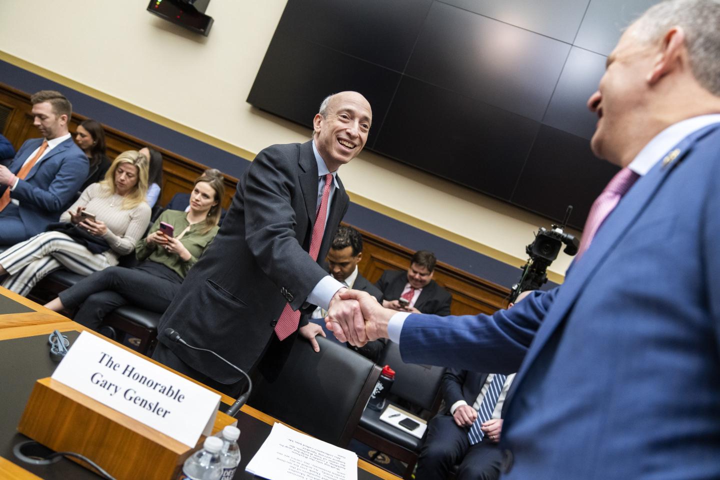 Gary Gensler shakes a congressman's hand.