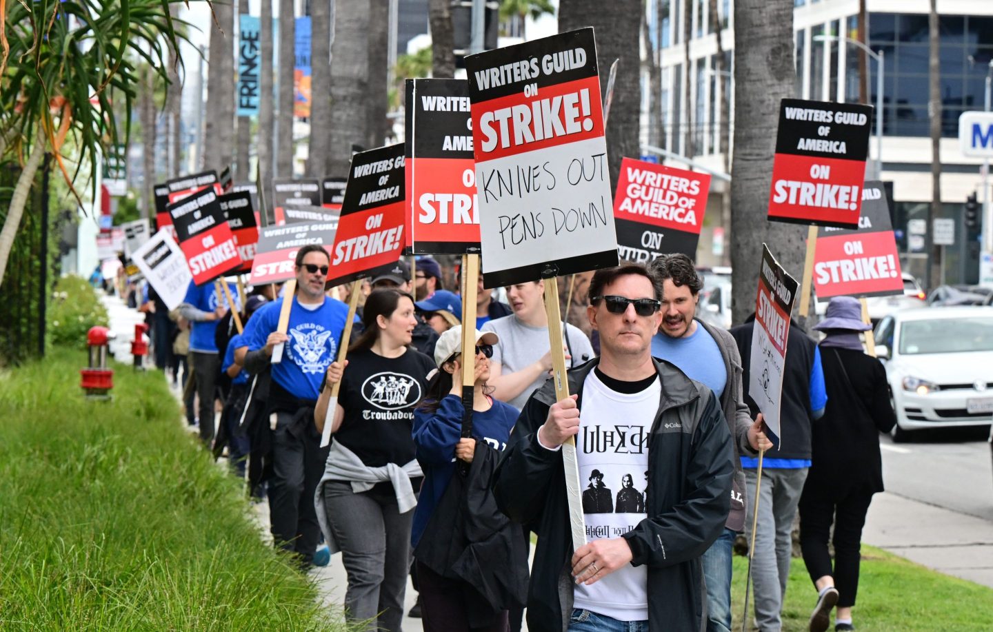 A group of people from the Writers Guild of America holding banners up while striking
