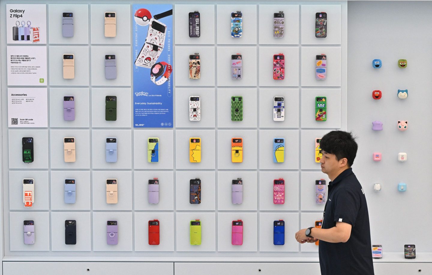 A man walks past accessories of the Samsung Galaxy Z Flip4 displayed on a wall during a media preview event for a new flagship store of Samsung Electronics at the Gangnam district in Seoul on June 28, 2023.