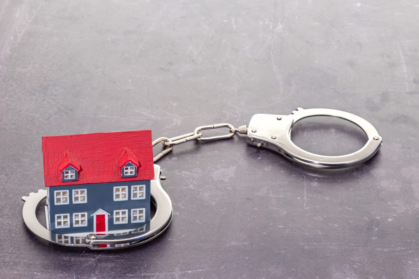Small model of a home caught in handcuffs