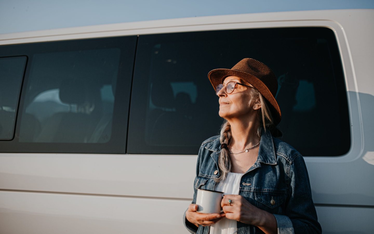 Senior woman resting outdoors at sunset, caravan trip holiday.