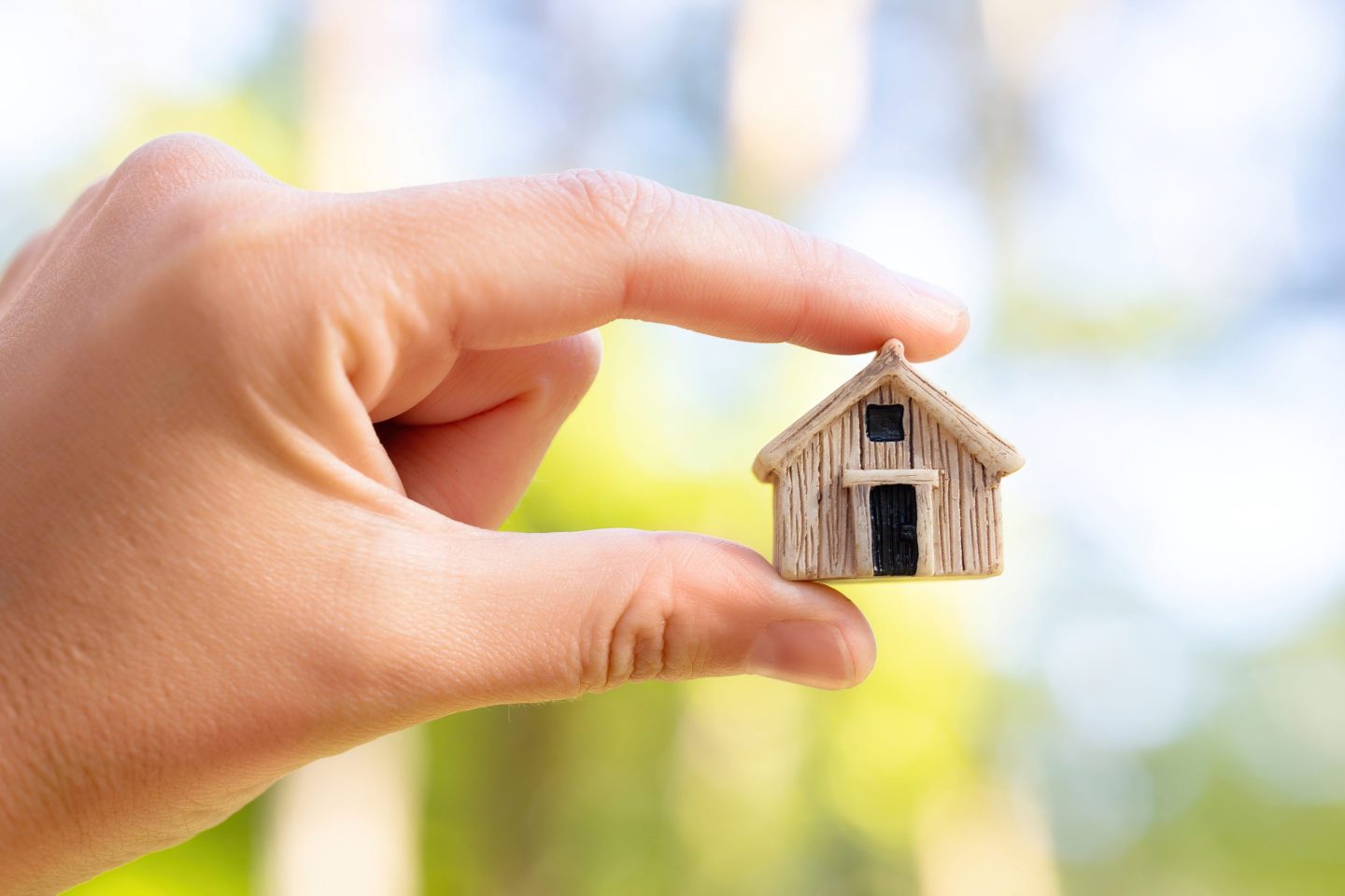 Photo of a person’s hand holding a model of a tiny house
