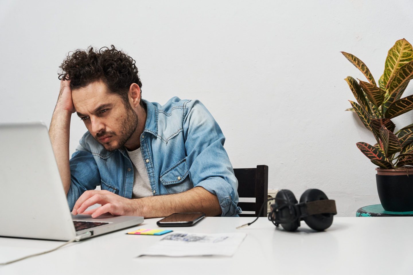 A person sitting at a desk with a laptop, looking stressed