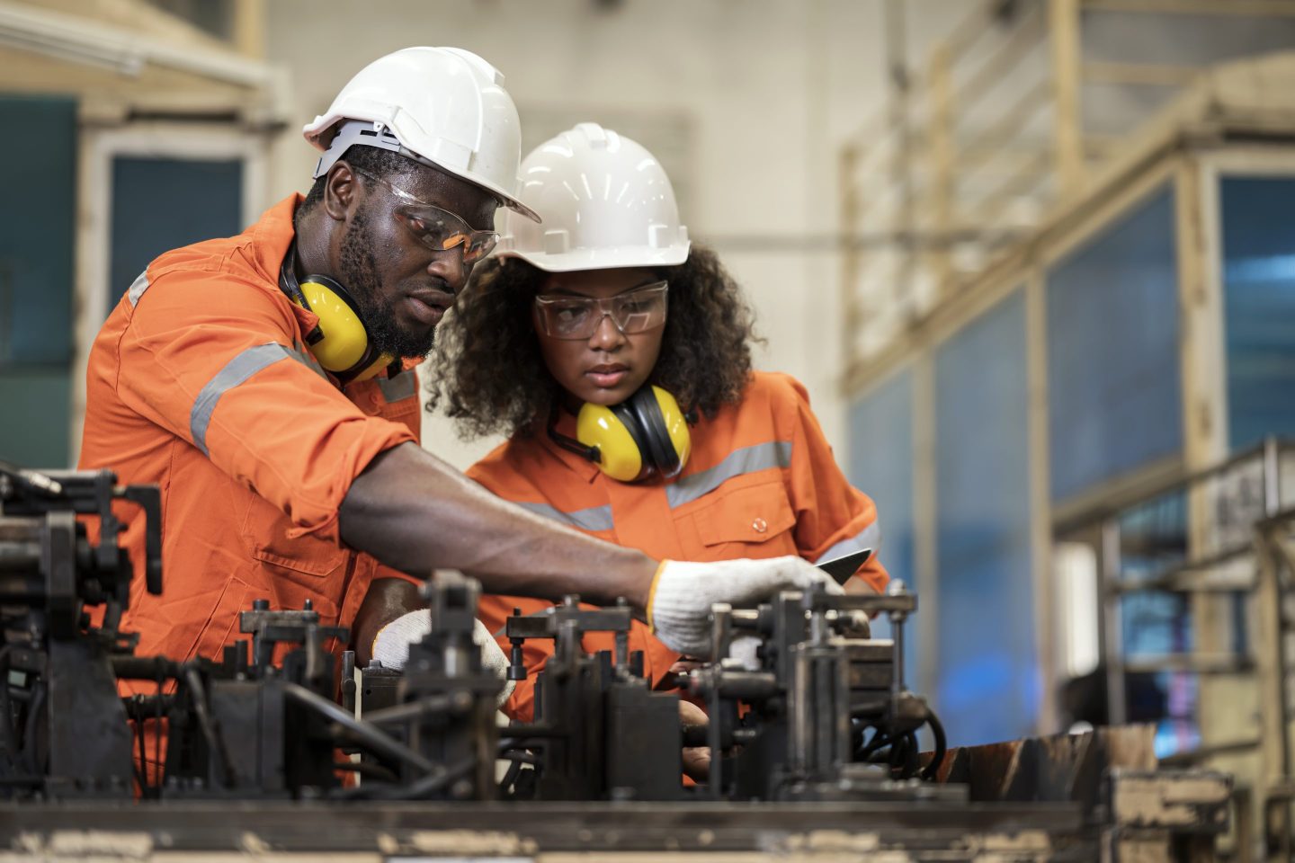 Engineers in hard hats and orange uniforms at work.