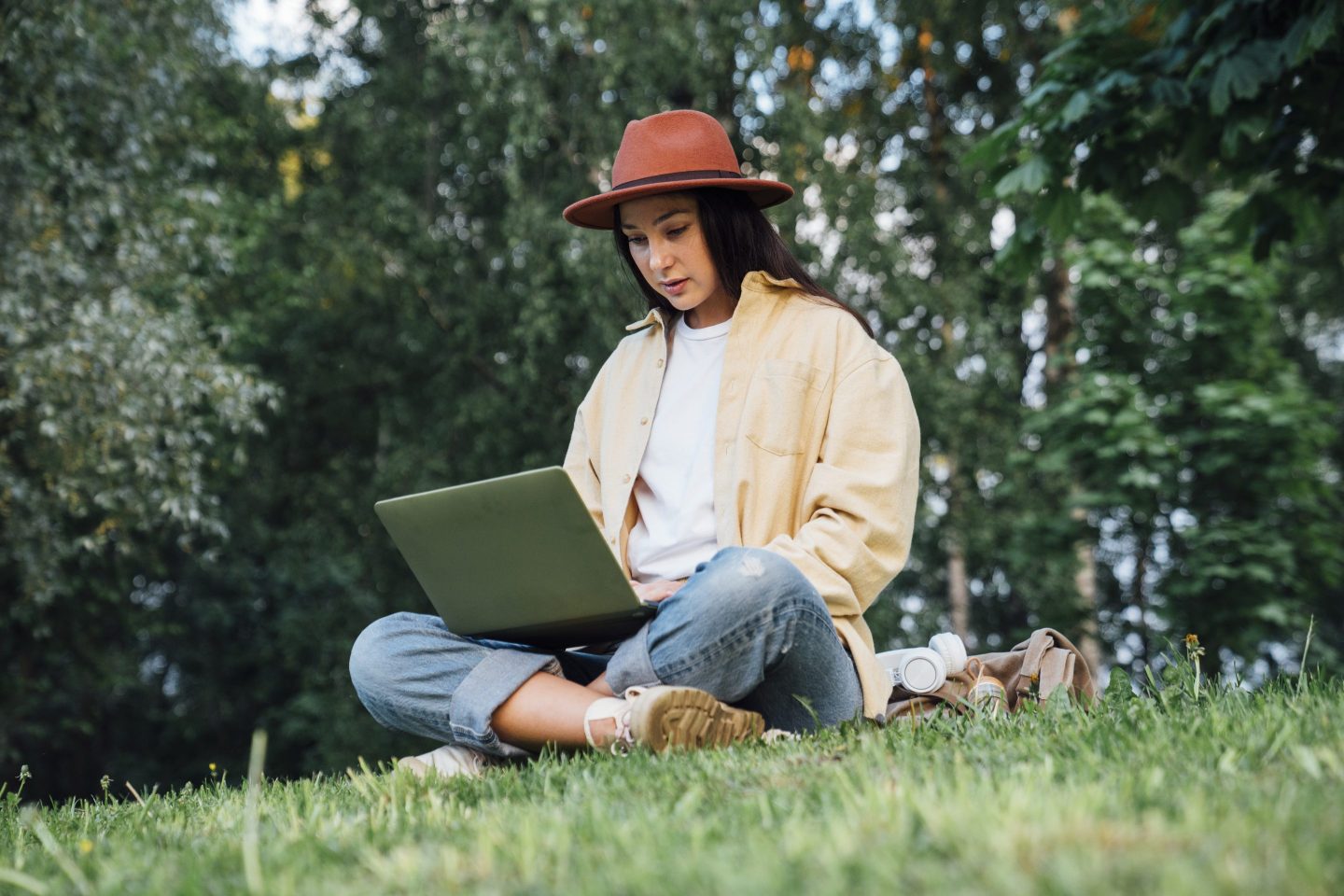 a woman working on her laptop and sitting in a park