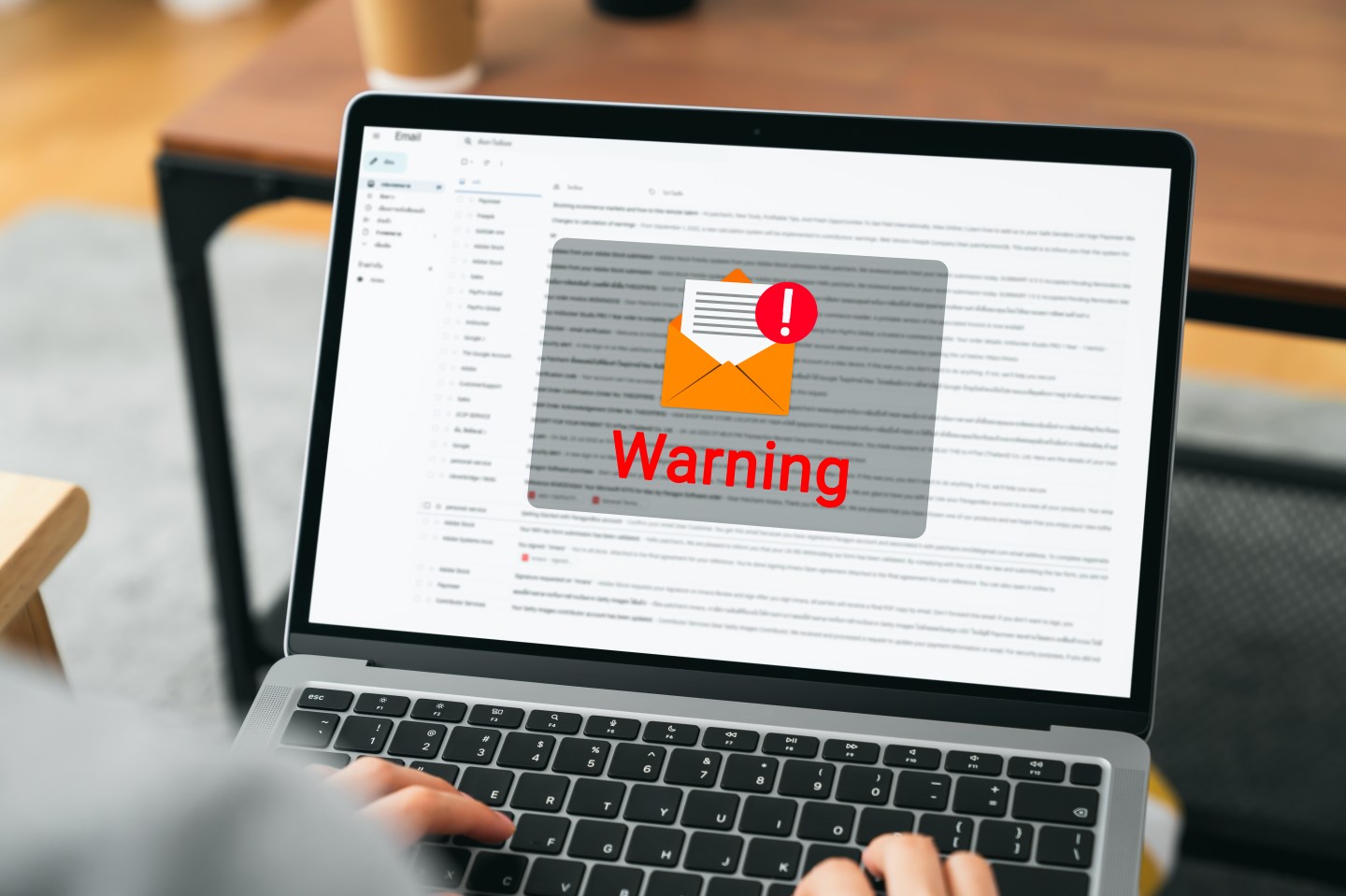 Hand using laptop with shows a warning screen of new email