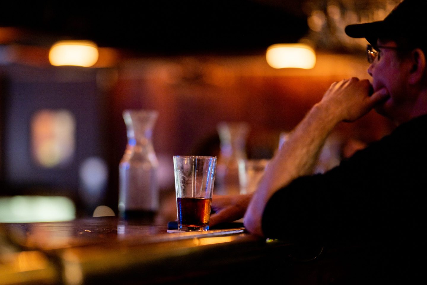 Photo of a person sitting at a bar and drinking a beer