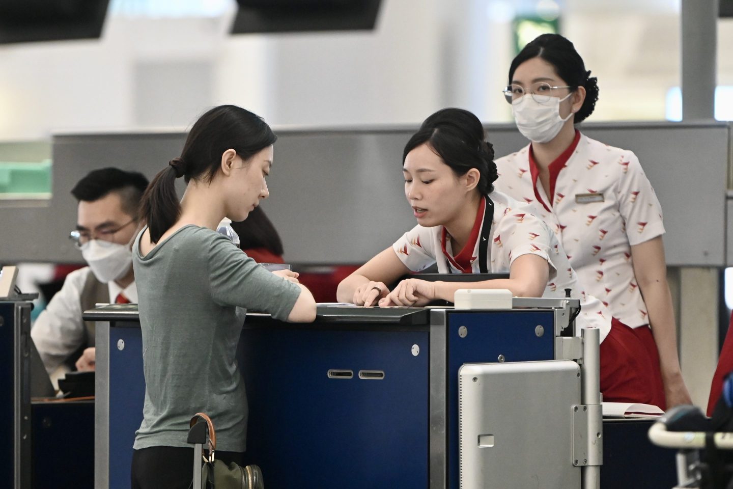 Attendants serve a passenger at the Cathay Pacific Airways check-in area at the Hong Kong International Airport on May 24, 2023.
