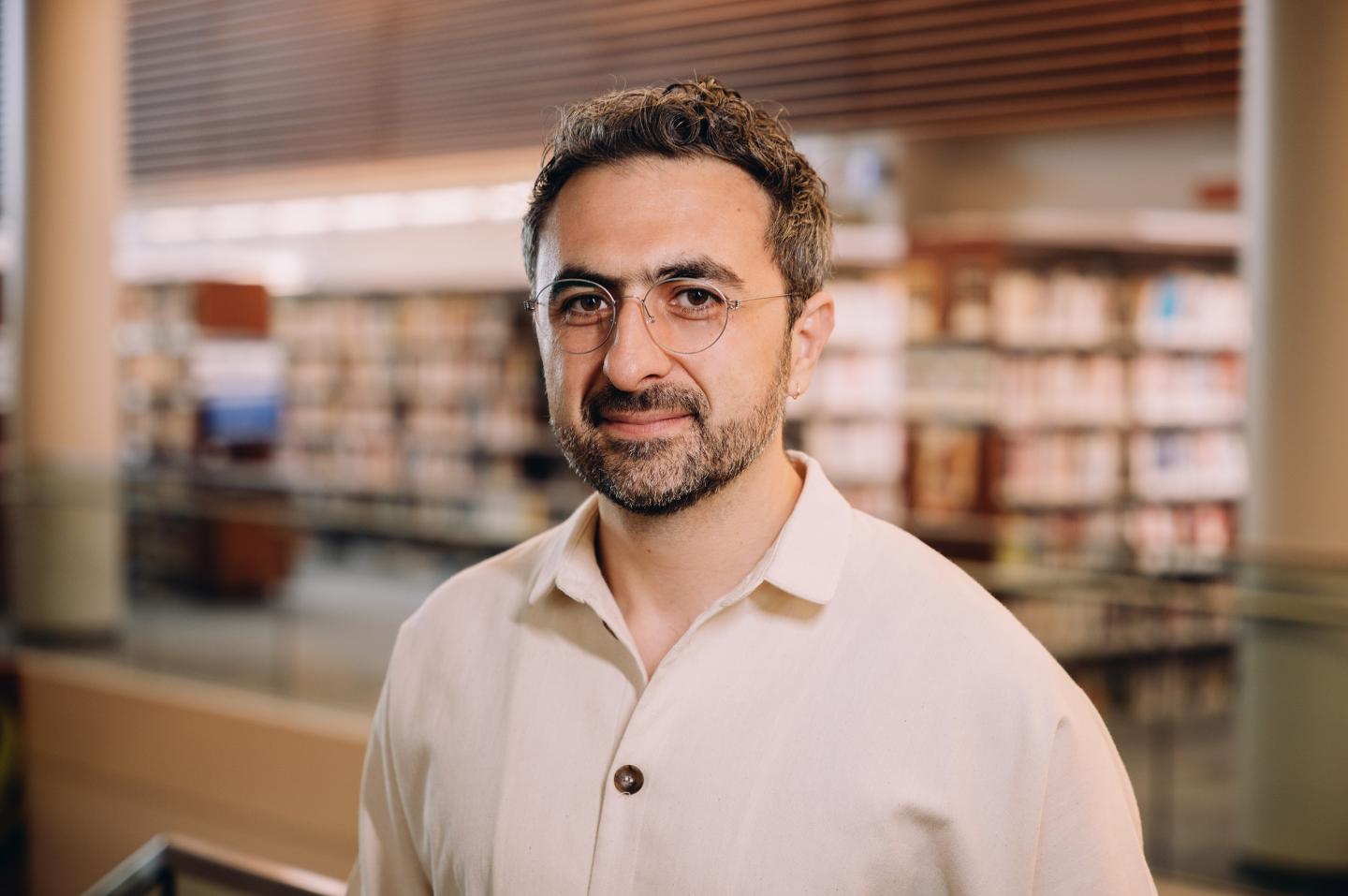 Mustafa Suleyman wears glasses and a button up.