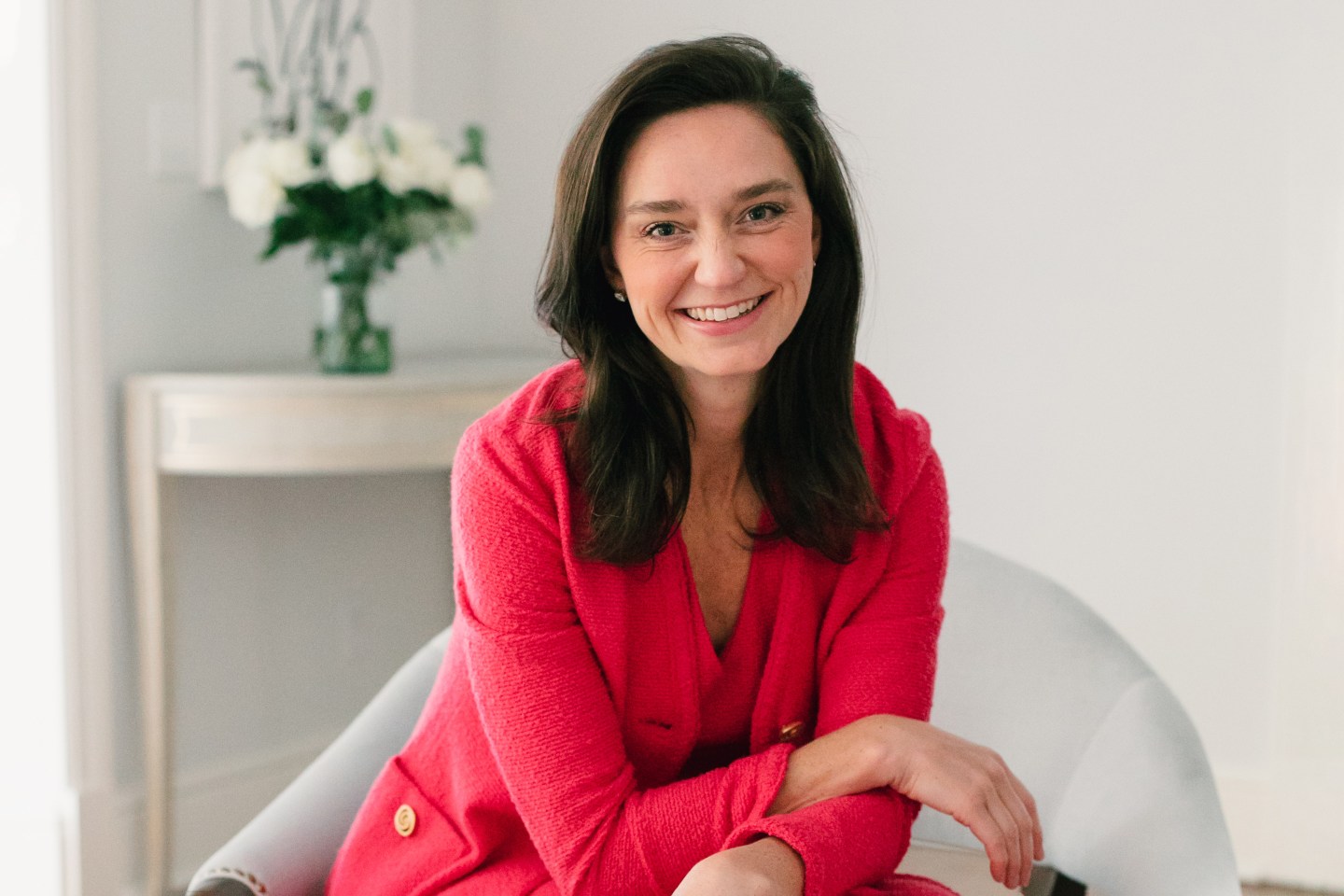 Woman wearing red clothing, sitting in a chair and smiling
