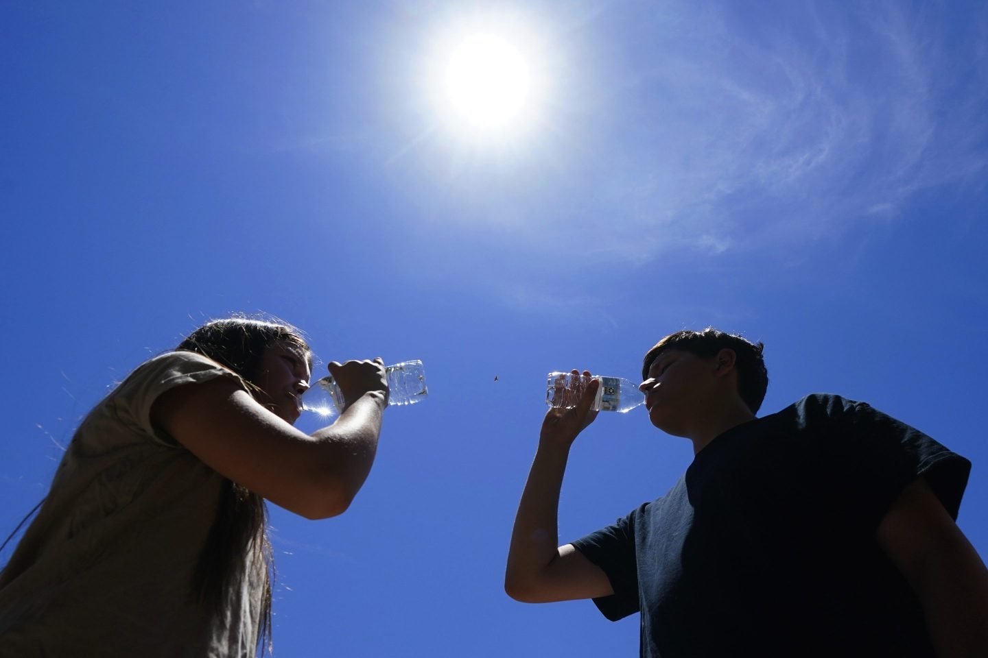 Tony Berastegui Jr., 15, right, and his sister Giselle Berastegui, 12, drink water as temperatures are expected to hit 115-degrees, on July 17, 2023, in Phoenix.