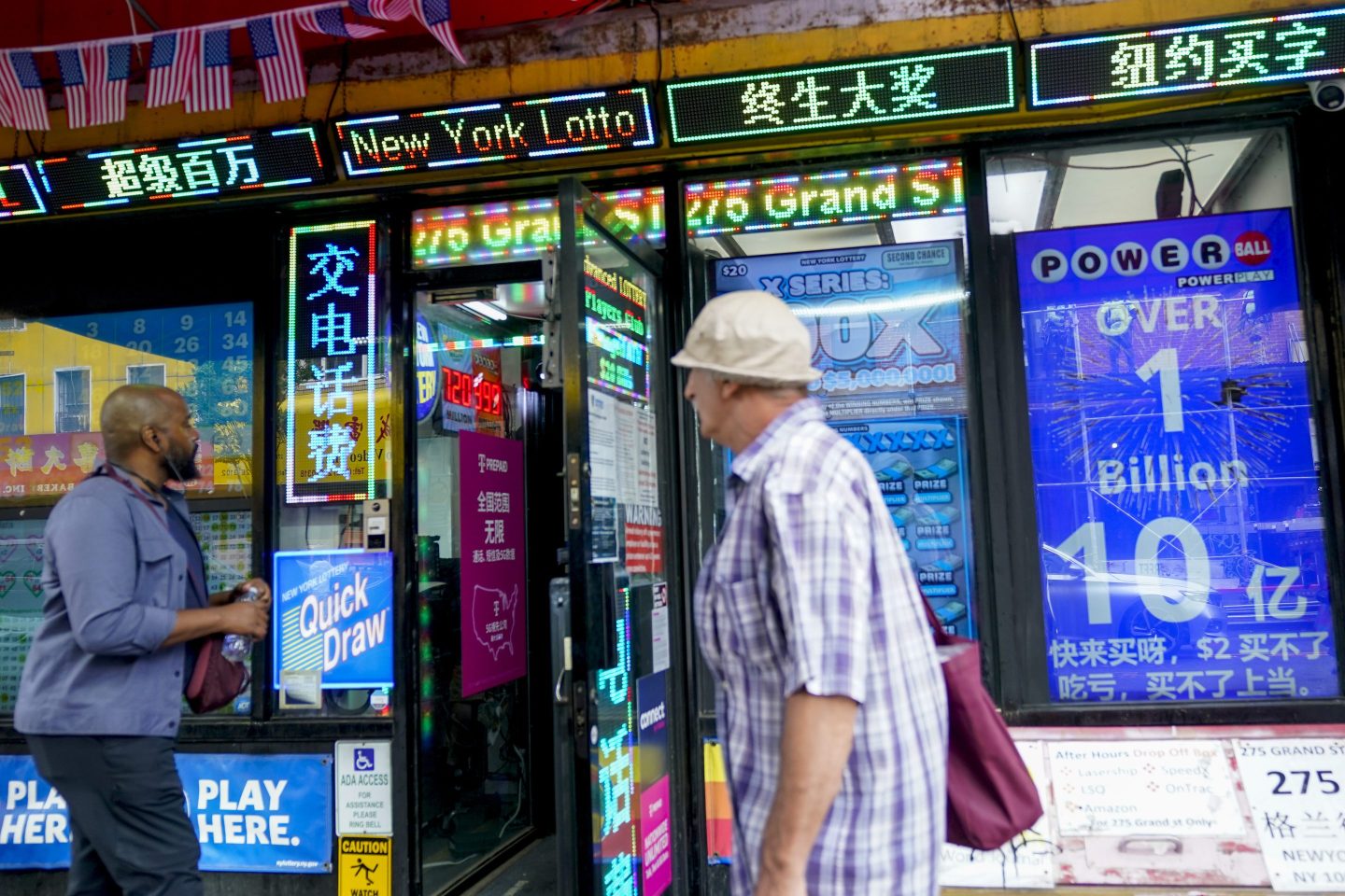 Pedestrians walk past an electronic sign hanging at a convenience store announcing a Powerball jackpot exceeding $1 billion, on July 19, 2023, in New York.