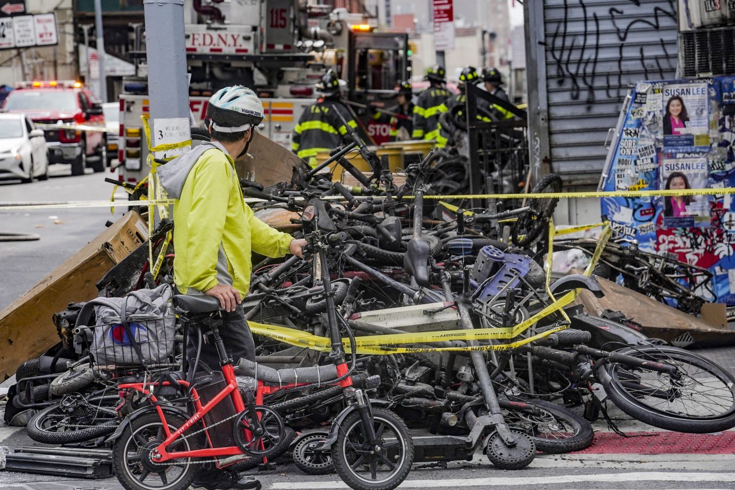 A biker stops to look at a pile of e-bikes in the aftermath of a fire in Chinatown, which authorities say started at an e-bike shop and spread to upper-floor apartments, on June 20, 2023, in New York.