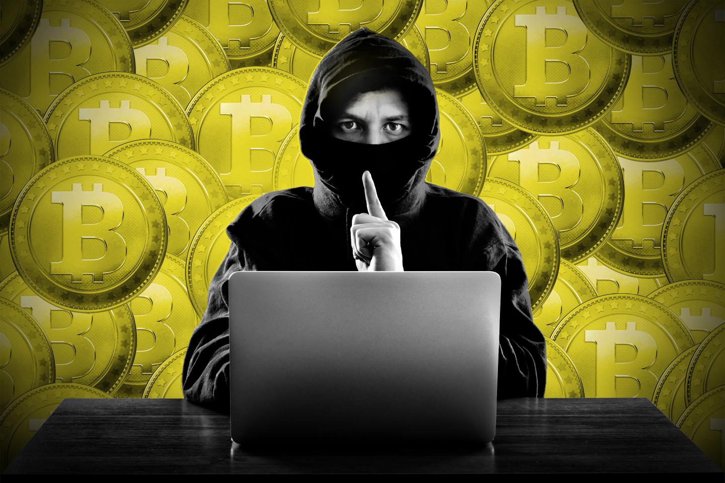 Hooded computer hacker stealing information with laptop.