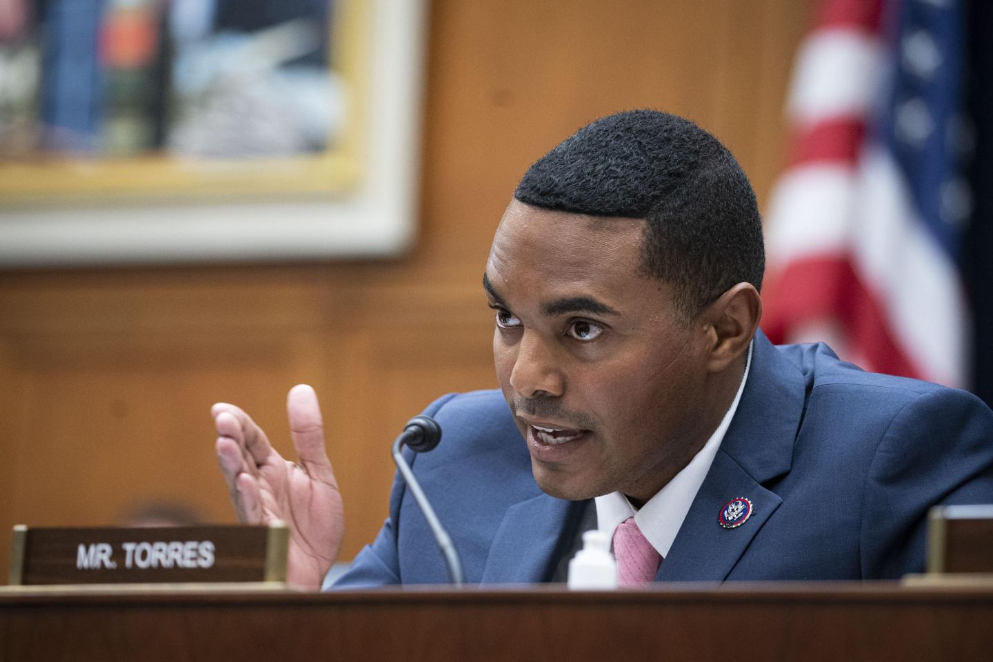 Man in navy suit and tie speaking into a microphone