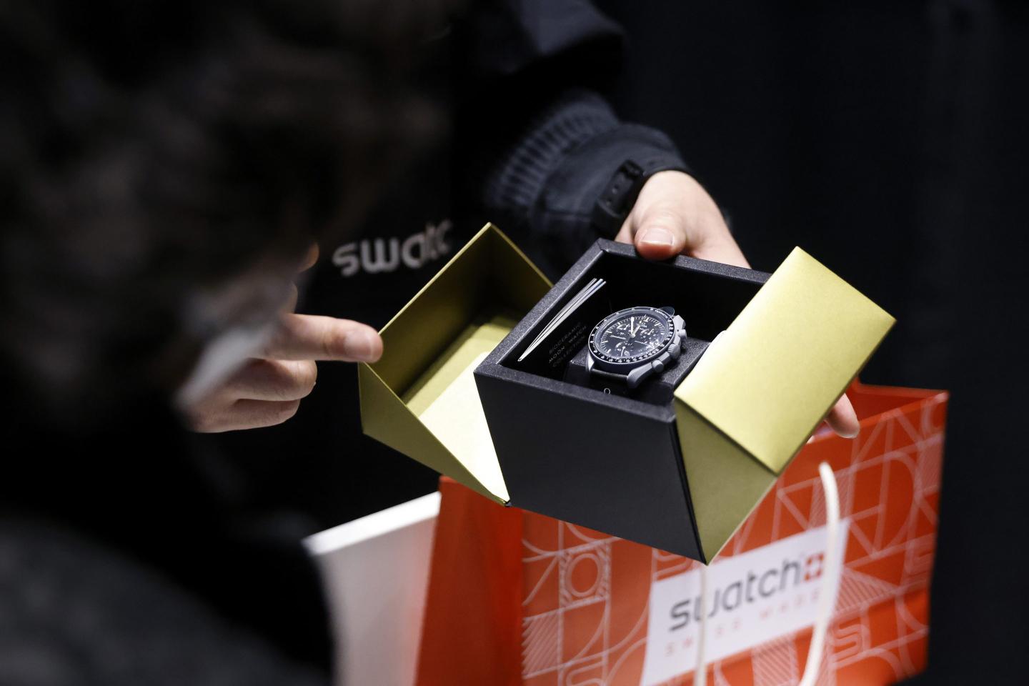 A customer buys the new edition Swatch AG Mission to Moonshine Gold MoonSwatch at its launch event in Tokyo, Japan
