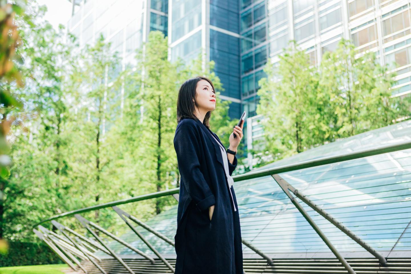 A woman standing in front of a corporate building with trees