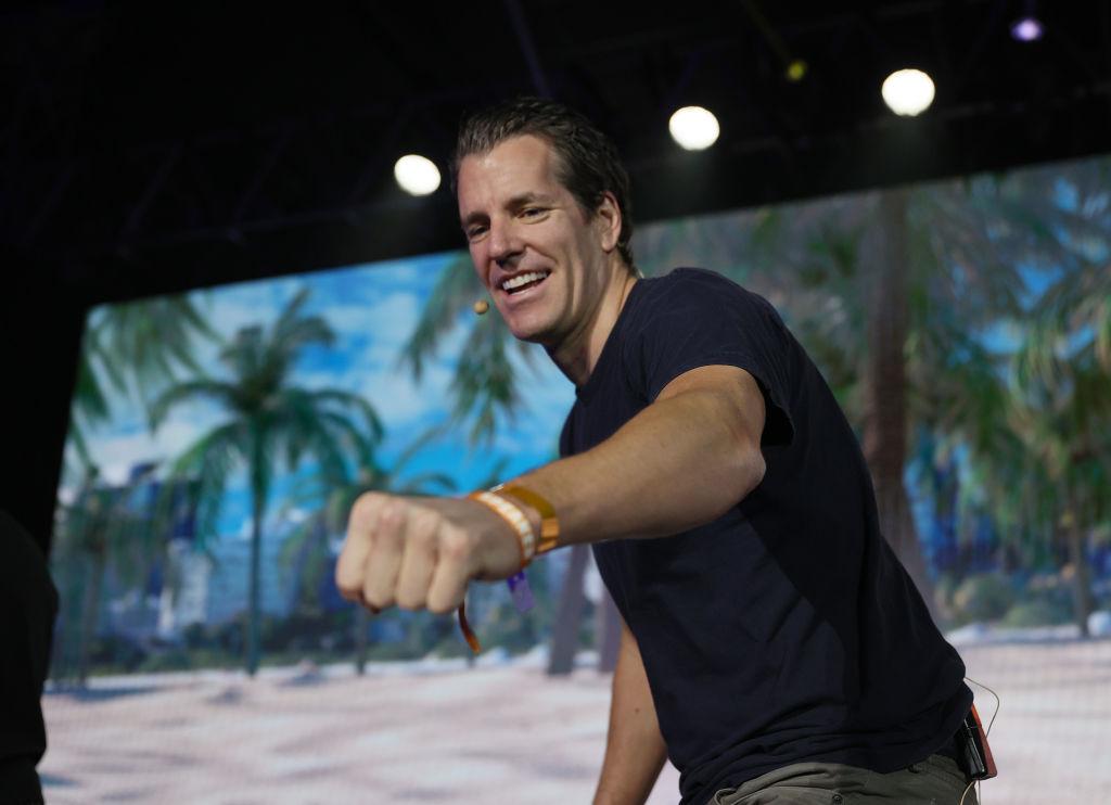 A man in a black t-shirt puts his hand out for a fist bump while on stage