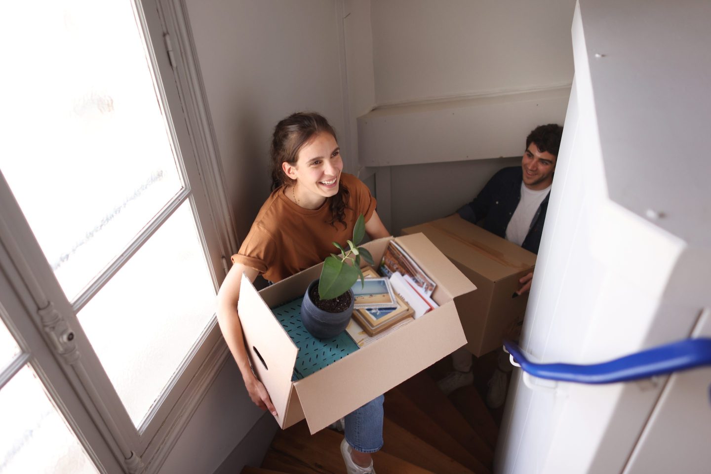 A person carrying a box of random items up a flight of stairs