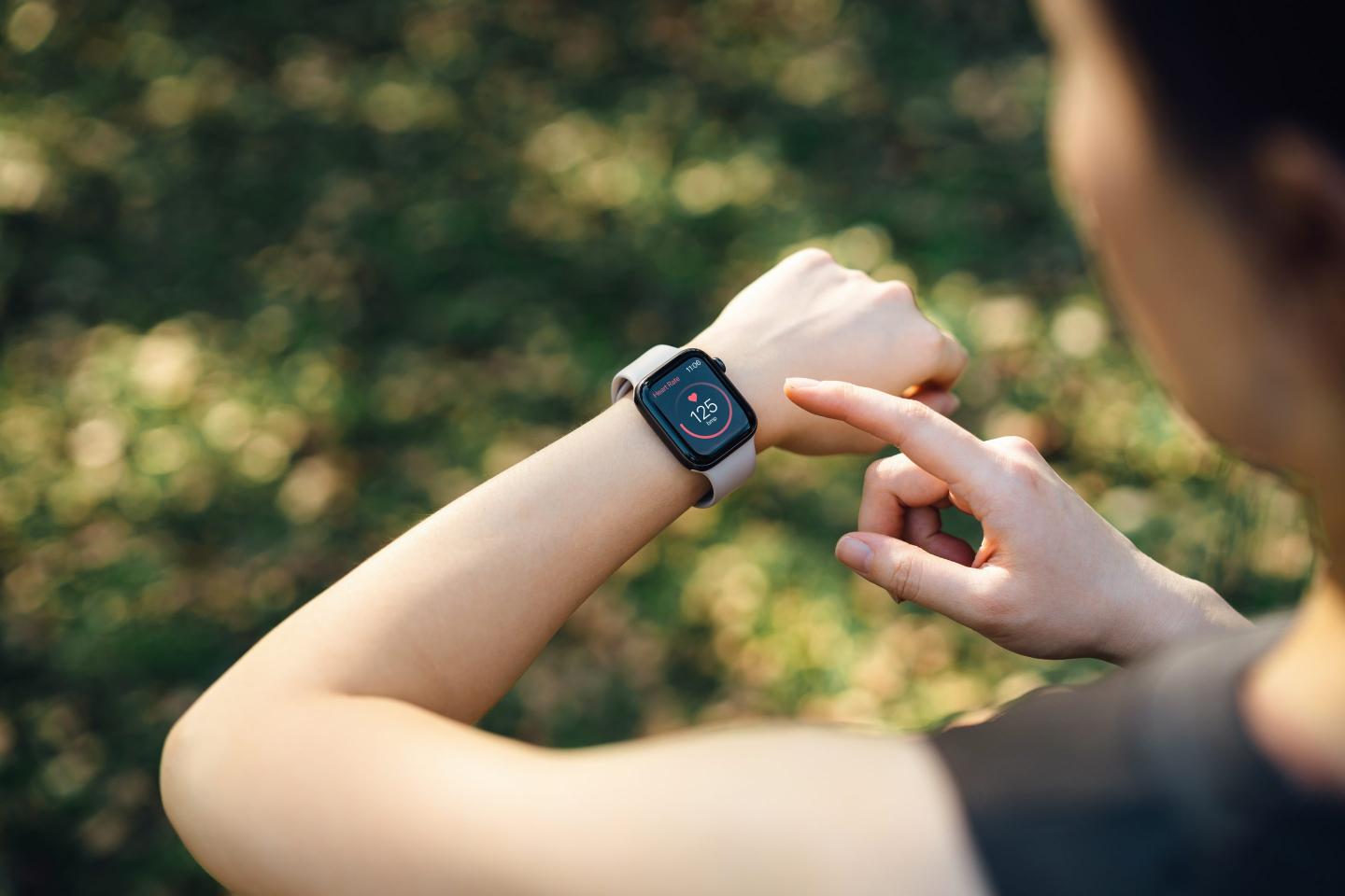 A person looking at a smartwatch showing a heart rate.