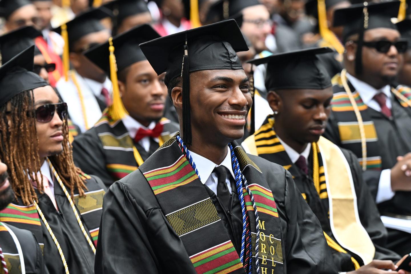 A student dressed in a cap and gown smiles during his college graduation.
