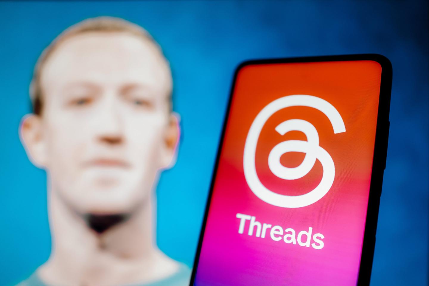 Threads logo is displayed on a smartphone screen with the image of Mark Zuckerberg, creator of the social network In the background