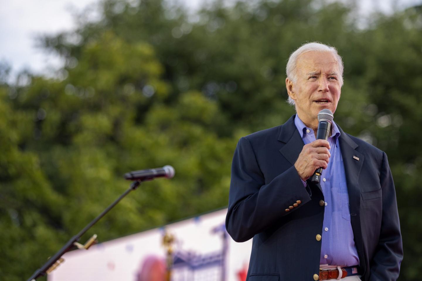 President Joe Biden holds a microphone as he gives a speech.
