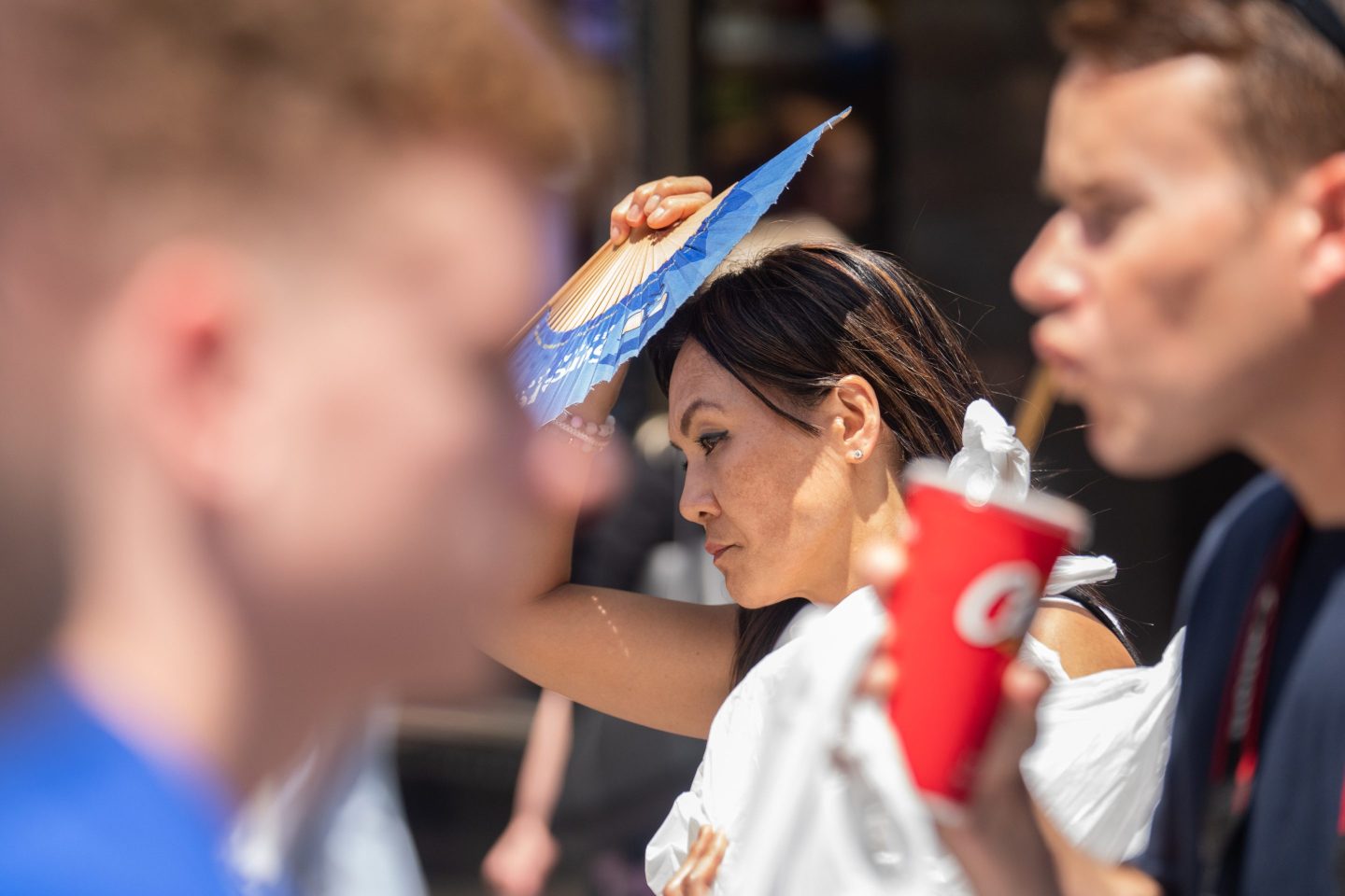 A pedestrian in New York holds a fan for protection from the sun.