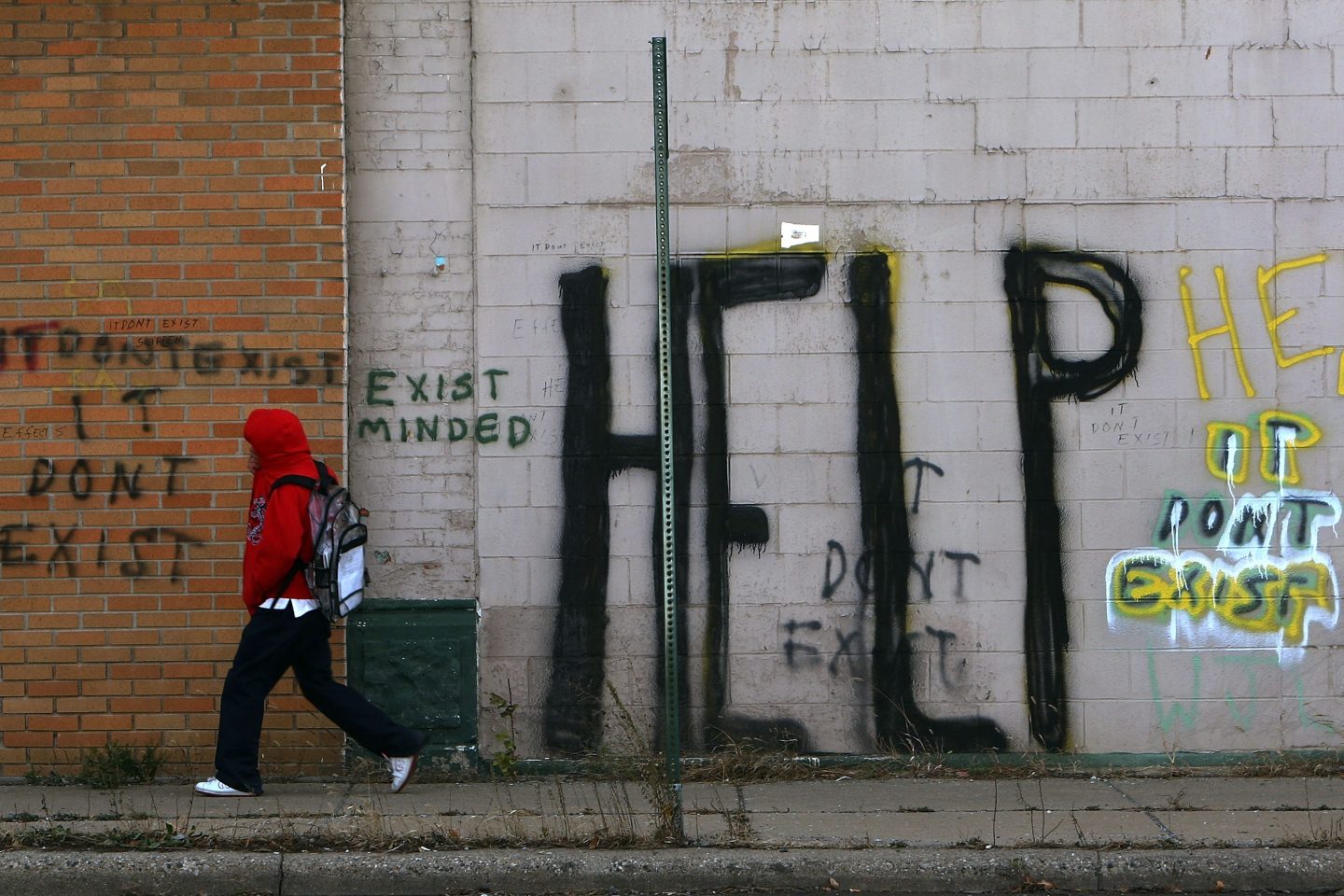 A pedestrian walks by graffiti on a downtown Detroit street
