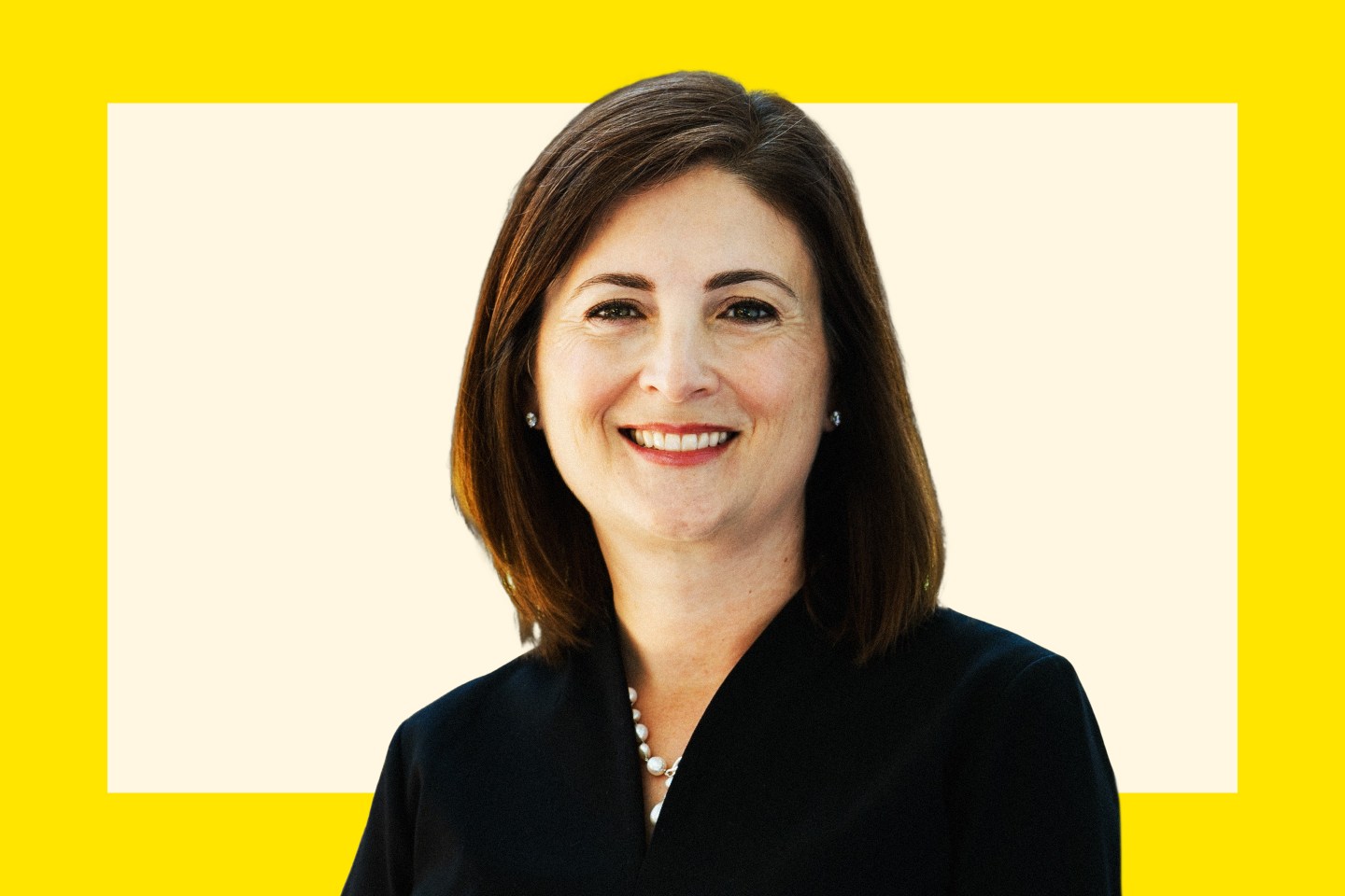 A woman with dark hair and wearing red lipstick looks directly at the camera smiling