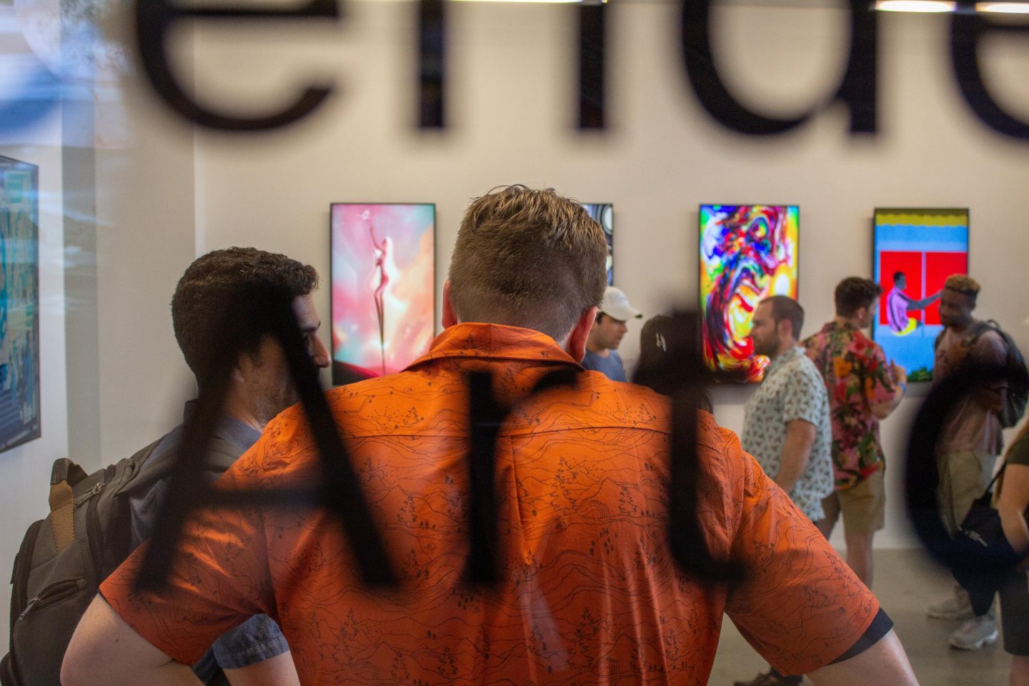 A view of a crowd the window of the NFT gallery.
