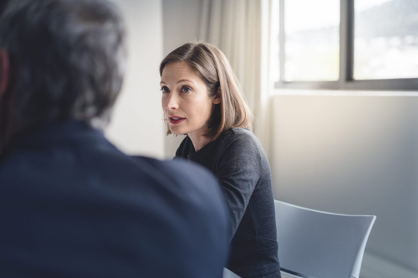 Mid adult businesswoman looking at colleague during meeting in board room in office