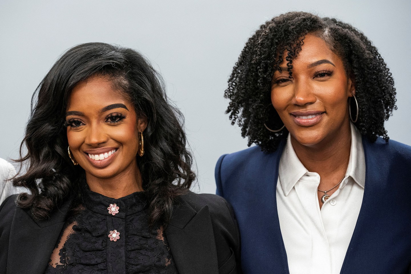 Two women in professional attire smiling onstage