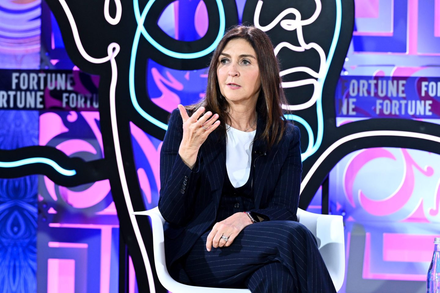 woman in suit jacket sitting and speaking onstage