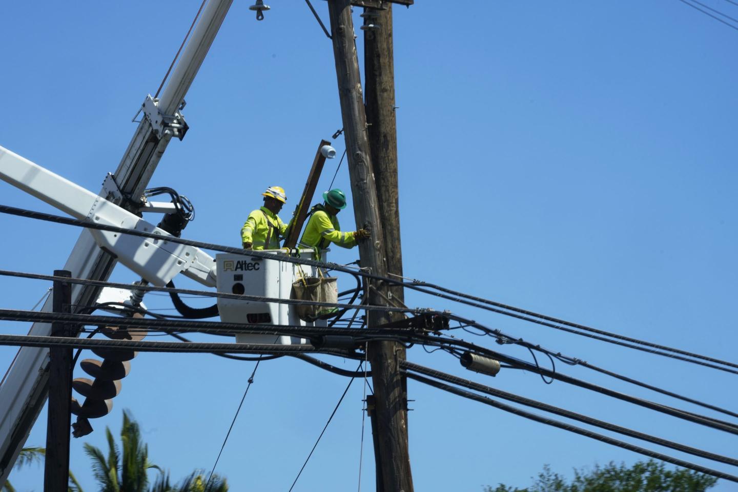 Linemen work on poles Aug. 13, 2023, in Lahaina, Hawaii, following a deadly wildfire that caused heavy damage days earlier.