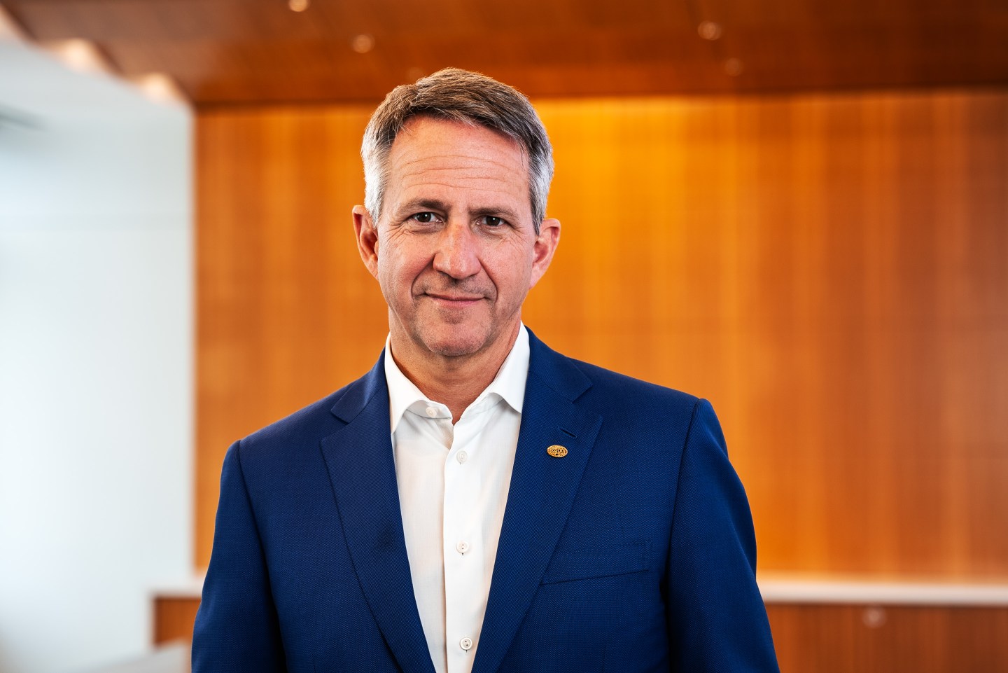 Portrait of EcoLab CEO Christophe Beck in front of wooden wall.