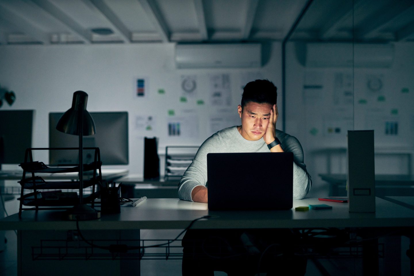 A young man looking stressed sitting alone in front of laptop.