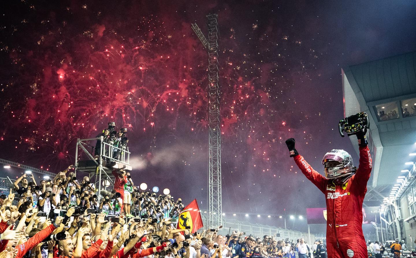 Sebastian Vettel celebrates with photographers around him.