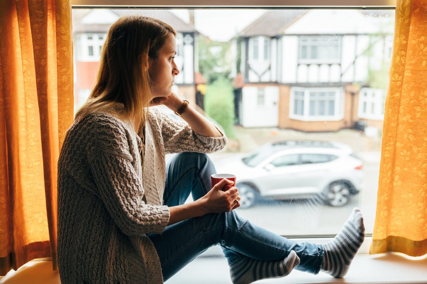 a woman sitting by a window sill and looking outside