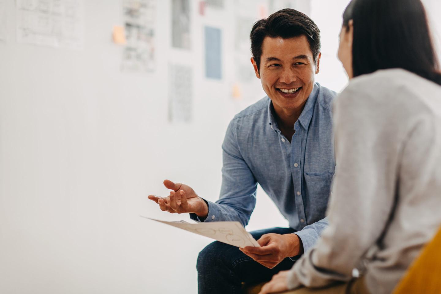 Male graphic designer shares ideas with female coworker during meeting in modern office studio.