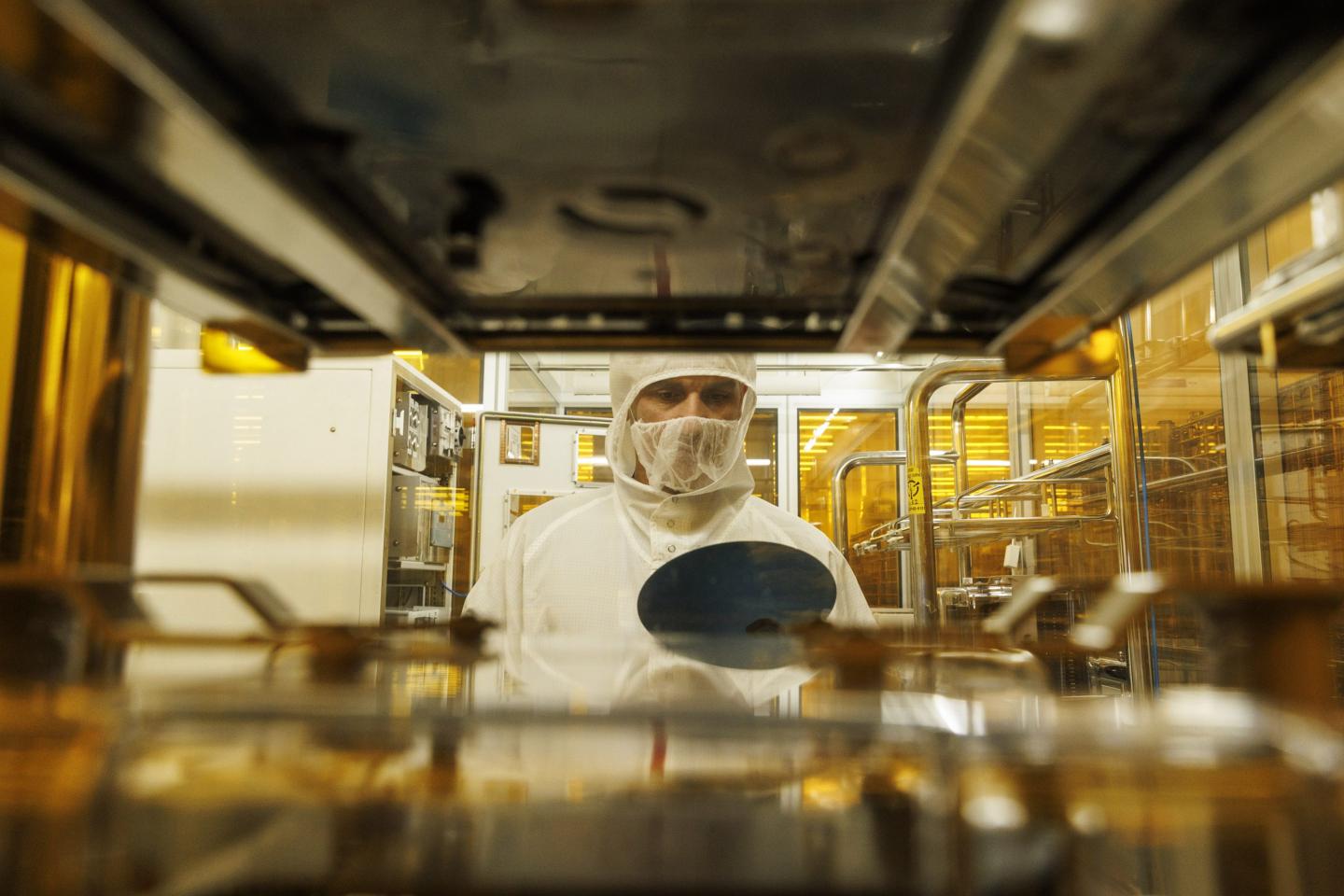 A technician inspects a semiconductor wafer during testing in the cleanroom