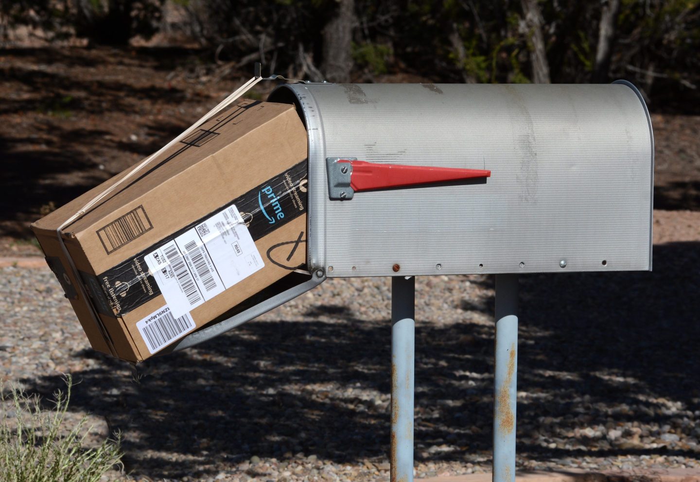 An Amazon package hanging out of a slightly too-small mailbox