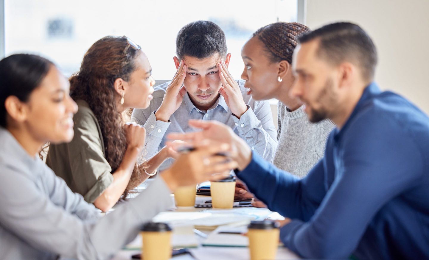 Shot of a young businessman looking stressed out in a meeting at work.