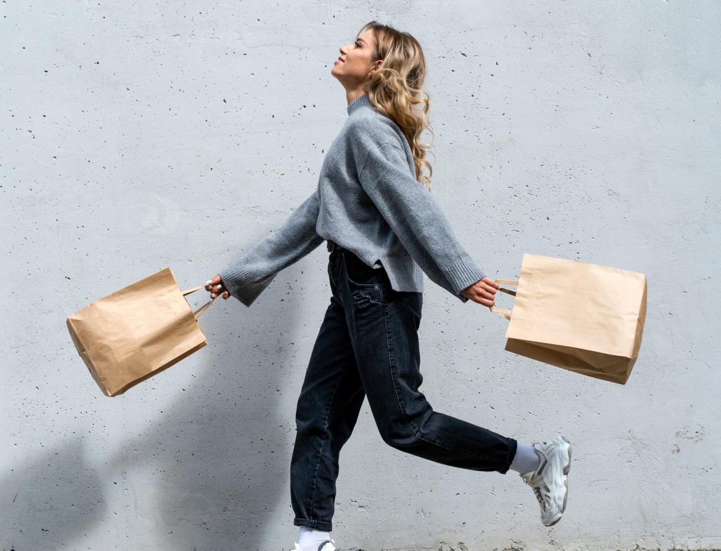 Woman holding two shopping bags running down the street